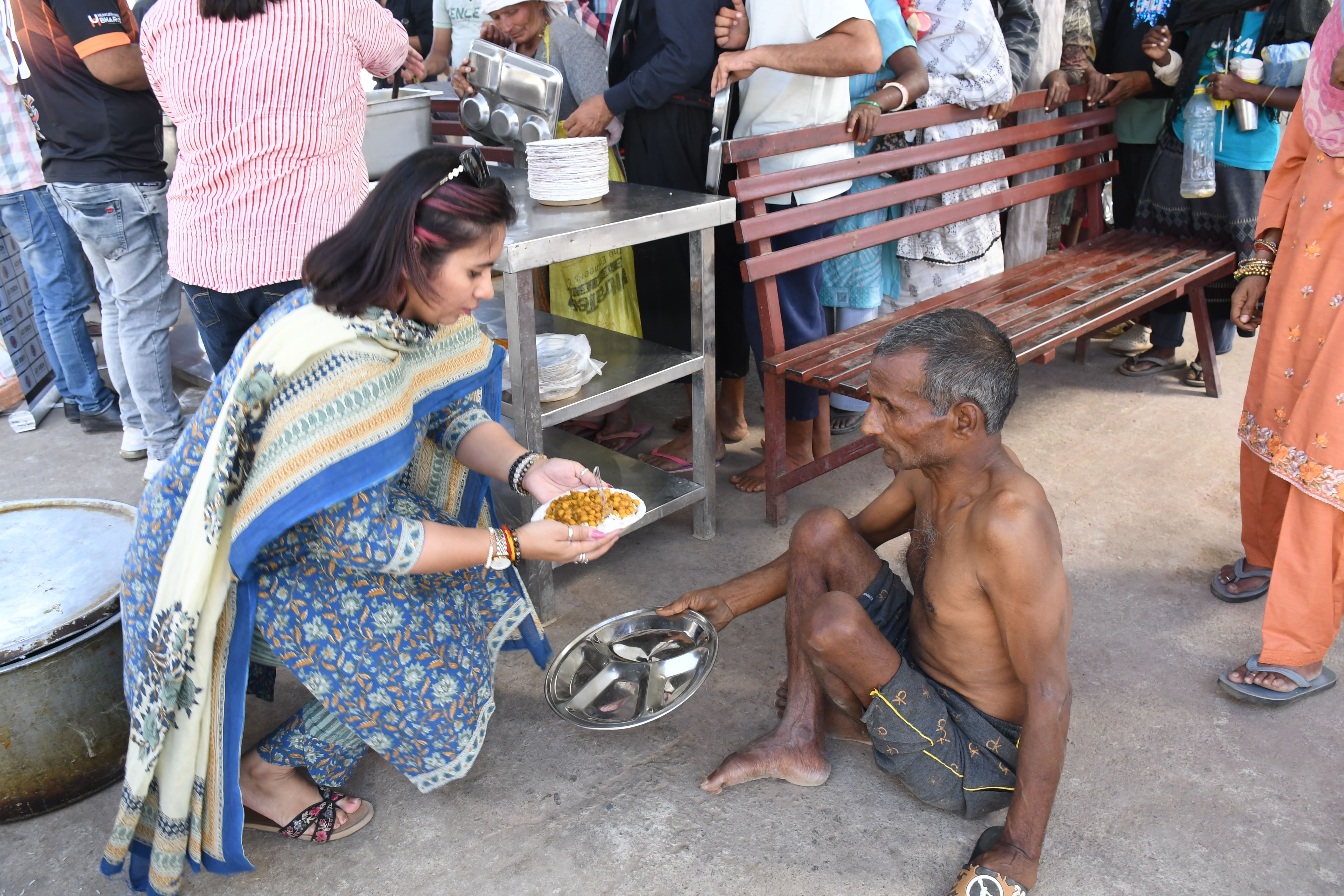 A volunteer serving a warm, dignified plate of fresh food to a recipient